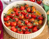 Konfierte Tomaten in einer Auflaufform, mit Brot und Knoblauch daneben.