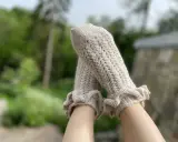 Piernas con calcetines de crochet color crema, con volantes en los tobillos y un delicado patrón calado.