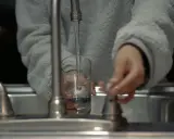Mano llenando un vaso con agua del grifo, un problema común con el agua dura en España.