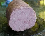 Pokrojona mielonka z szynkowara, różowa i soczysta, leży na ciemnej, karbowanej paterze.