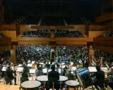 Orquesta sinfónica tocando para un público numeroso. Un director dirige la orquesta, creando una atmósfera mágica para los conciertos infantiles.