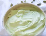 Un bol rempli de ganache pistache onctueuse, parsemé de pistaches entières. Une gourmandise verte et appétissante.
