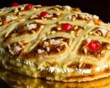 Deliciosa coca de Sant Joan rellena de crema, decorada con piñones, cerezas rojas y azúcar.