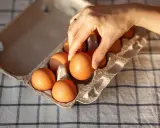 Dłoń wybiera jajko z wytłoczki. Zastanawiasz się, ile kcal ma jajko? To zdrowa przekąska!