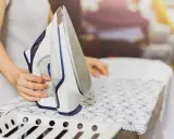 Persona plancha un vestido de satén con cuidado en una tabla de planchar.