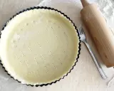 Surowe ciasto wegańskie w formie do tarty, obok wałek i widelec. Gotowe do pieczenia pysznego deseru.