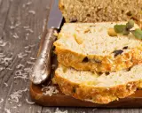 Pokrojona babka z cukinii z ziołami i serem, ułożona na desce, obok nóż.