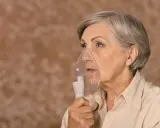 Starsza kobieta z maską nebulizatora, która może pomóc w leczeniu zapalenia płuc. Rokowania zależą od wielu czynników.