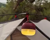 En mysig campingbelysning hänger från tältstången och lyser upp kvällen.