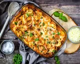 Herzhafter Tortellini Auflauf mit Erbsen und Pilzen, überbacken mit Käse und garniert mit frischem Basilikum.