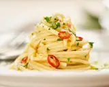 Ein Berg Spaghetti Aglio e Olio, garniert mit frischer Petersilie und scharfen Chilischeiben.