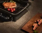 Idealne grillowanie na grillu elektrycznym. Soczysty stek z pomidorkami i rozmarynem, a obok pokrojone mięso na desce.