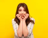 Ragazza con espressione preoccupata che si mangia le unghie, un chiaro segno di gestione dell'ansia.