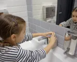 Niña se lava las manos en el baño, un gesto importante para la higiene y la prevención del toc en niños.