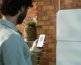 Man kollar sin mobil som visar information om sin batteribank hemma.