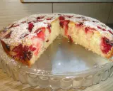 Wilgotne ciasto ucierane z owocami, posypane cukrem pudrem, prezentuje się apetycznie na szklanej paterze.