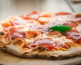 Eine köstliche italienische Pizzateig-Pizza mit Salami und Basilikum, frisch aus dem Ofen.
