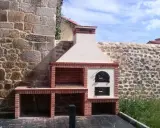 Barbacoa de obra con horno de leña y fregadero, lista para disfrutar de una comida al aire libre.