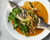 Ein ganzer Wolfsbarsch Fisch, gedünstet in einer würzigen Sauce mit Ingwer und Frühlingszwiebeln, garniert mit Koriander.