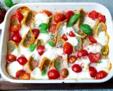 Herzhafter Maultaschen Auflauf mit Kirschtomaten und geschmolzenem Mozzarella, garniert mit frischem Basilikum.
