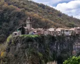 Castellfollit de la Roca, un pueblo medieval colgado sobre un acantilado basáltico, se alza majestuoso entre bosques otoñales.