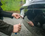 Ręce przykręcają tablicę rejestracyjną do zderzaka. Ubezpieczenie OC niezarejestrowanego auta jest kluczowe przed jazdą.
