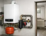 Nowoczesny kocioł gazowy do układu otwartego, z cyfrowym wyświetlaczem i widocznym manometrem, podłączony do instalacji grzewczej.