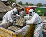 Osoby w kombinezonach ochronnych usuwają eternit, materiał zawierający azbest. Co to jest azbest? To niebezpieczny materiał budowlany.