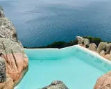 Piscina a sfioro incastonata tra rocce granitiche, con vista sul mare blu intenso. Un angolo di paradiso, forse un progetto di Alberto Ponis.