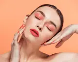 Maquillajes Euphoria: ojos con sombra coral brillante y labios rojos vibrantes, uñas a juego.