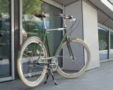 Stylowy, zielony rower do miasta z brązowym siodełkiem i uchwytami, gotowy na miejskie przygody.