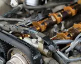 Motor de coche con correa de distribución y árbol de levas dorado. Se observa posible desgaste en el árbol de levas.