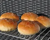 Fünf goldbraune Burgerbrötchen mit Sesam, perfekt für ein Burgerbrötchen-Rezept.