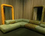 Salon w stylu vintage: zielona, modułowa kanapa i dwa lustra w ozdobnych, żółto-zielonych ramach.