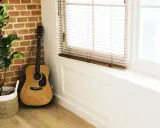 Gitara akustyczna obok ceglanej ściany i rośliny w koszu. Idealne miejsce na naukę piosenki na gitarę dla początkujących dzieci.