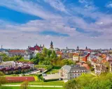 Widok na malownicze miasto w województwie lubelskim. Dachy kamienic, kościoły i zieleń pod błękitnym niebem.