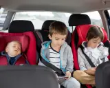 Dziecko śpi w foteliku, a dwaj starsi chłopcy grają na telefonach. Bezpieczeństwo przede wszystkim, ale od jakiego wzrostu bez fotelika?