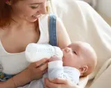 Mamma con capelli rossi nutre il suo neonato con latte artificiale ogni 2 ore. Il piccolo beve con gusto dalla bottiglia.