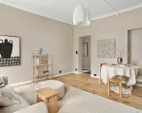 Salón con paredes color crema, ideal para inspirarse sobre de que color pintar la casa. Muebles de madera clara y arte abstracto.