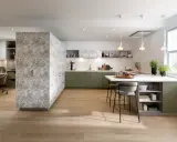 Cuisine moderne avec îlot central, murs décorés de motifs végétaux. Quel mur peindre en couleur ? Les meubles verts s'harmonisent avec le bois clair.