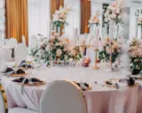 Eleganckie dekoracje stołów weselnych nowości: pastelowe kwiaty, złote świeczniki i ciemne serwetki tworzą romantyczny nastrój.