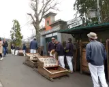 Korbschlitten Madeira: Männer in traditioneller Kleidung warten neben den Korbschlitten auf Fahrgäste.