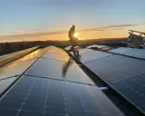 Arbetare installerar solpaneler på ett tak i solnedgången. Gosol Energi AB ser till att framtiden blir grön.
