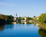 Vacker vy över Klarälven i Karlstad med stadens silhuett och grönska. Perfekt för promenader och andra aktiviteter Karlstad erbjuder.