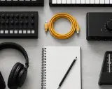 Clavier, casque, câble jaune, carnet, crayon, métronome et interface audio : tout pour une musique creative.