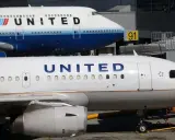 Dwa samoloty United Airlines na płycie lotniska. Jeden z nich to Boeing 747, drugi to mniejszy samolot. W tle widać budynek terminala.