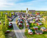 Kyrkstaden Luleå, en idyllisk by med röda hus och en kyrka, badar i solljus.