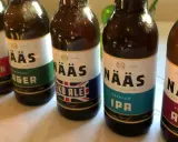 Flera flaskor öl från Nääs bryggeri står uppradade. En flaska med etiketten "Eko Ale" syns tydligt.