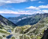 Majestatyczne Tatry Wysokie z doliną, dwoma stawami i skalistymi szczytami pod błękitnym niebem.