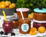 Marmelade ohne Gelierzucker haltbar machen: Mehrere Gläser mit selbstgemachter Marmelade, Früchten und Beeren.